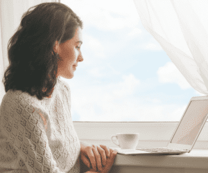 femme assise devant son ordinateur avec une tasse de café