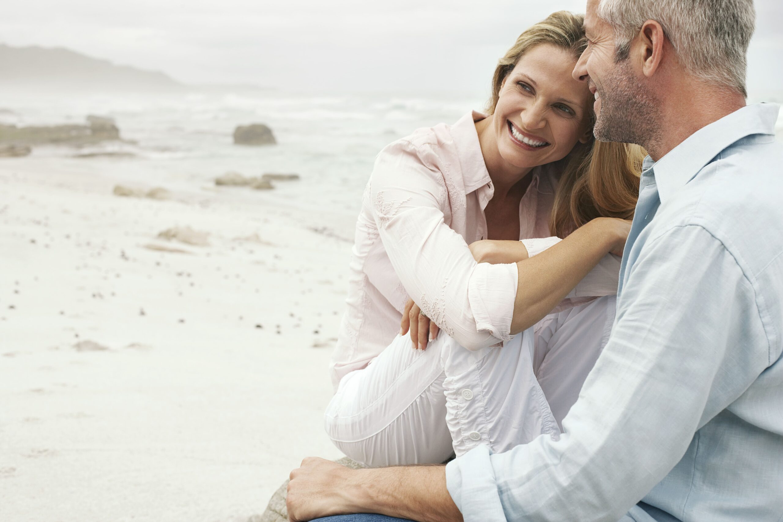 une femme heureuse assise sur le bord de la plage avec son conjoint