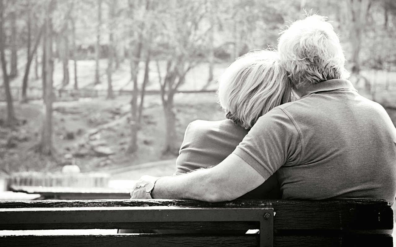 un couple plus âgés assit dans un parc en amoureux
